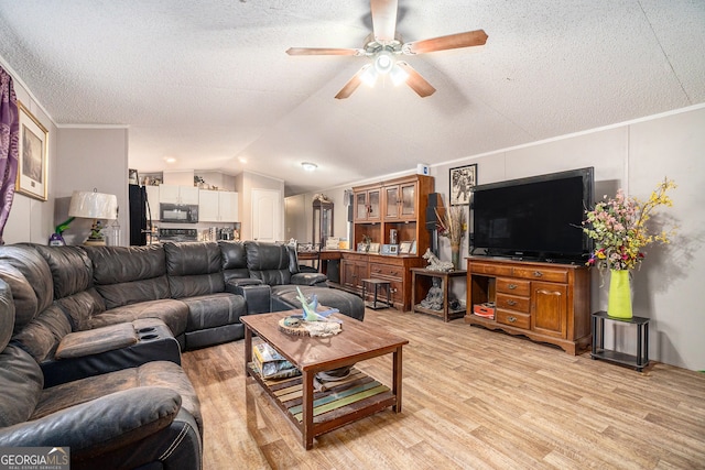 living room featuring a textured ceiling, ceiling fan, vaulted ceiling, and light wood-type flooring