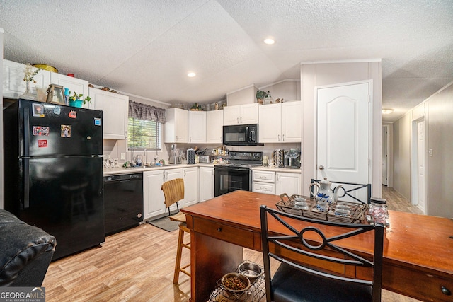 kitchen with white cabinets, light hardwood / wood-style floors, lofted ceiling, and black appliances