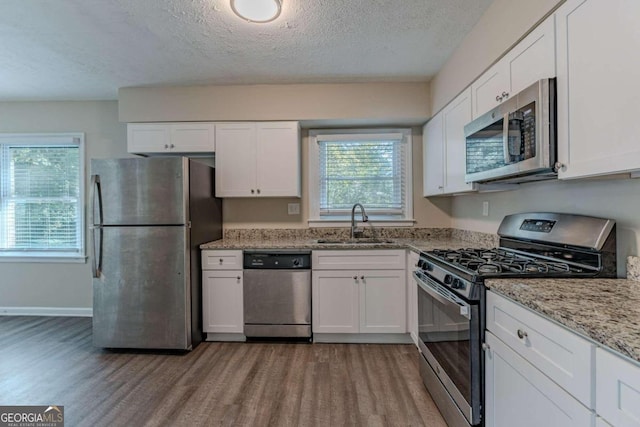 kitchen with sink, light hardwood / wood-style flooring, white cabinets, and appliances with stainless steel finishes