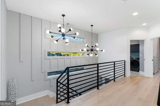 stairs featuring washer / dryer, hardwood / wood-style flooring, and a notable chandelier