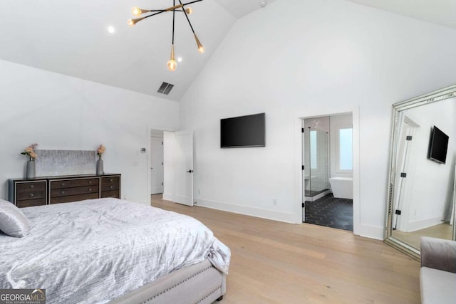 bedroom with connected bathroom, high vaulted ceiling, light hardwood / wood-style flooring, and a notable chandelier