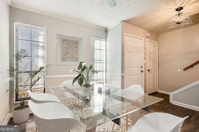 dining area with a chandelier, a textured ceiling, crown molding, and dark wood-type flooring