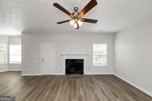 unfurnished living room with ceiling fan, dark hardwood / wood-style flooring, and a textured ceiling