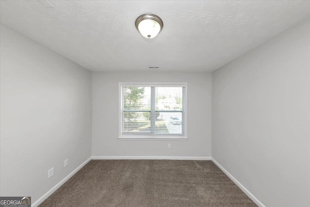 empty room featuring a textured ceiling and dark carpet