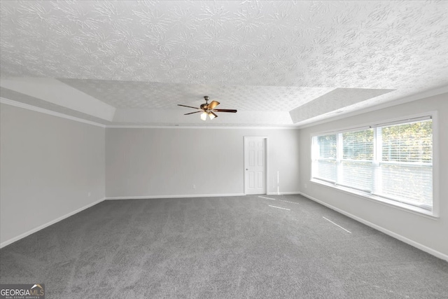 carpeted spare room featuring a textured ceiling, a raised ceiling, and ceiling fan