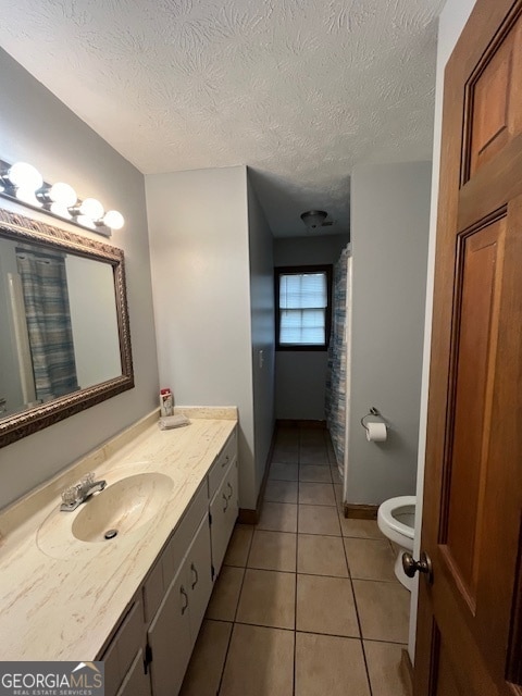 bathroom with tile patterned floors, vanity, a textured ceiling, and toilet