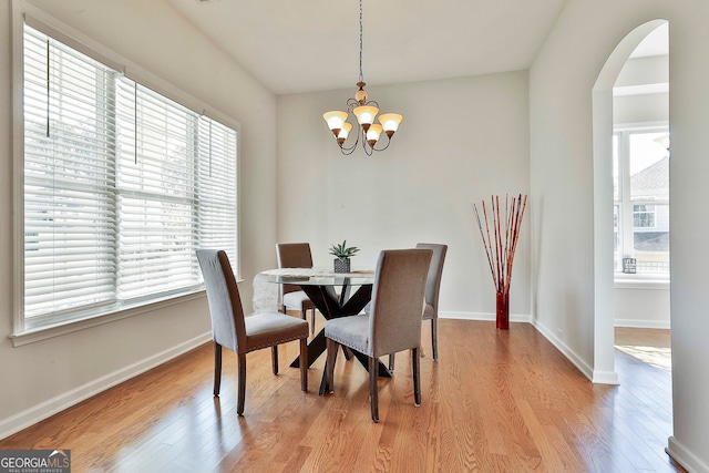 dining space with light hardwood / wood-style floors, an inviting chandelier, and plenty of natural light