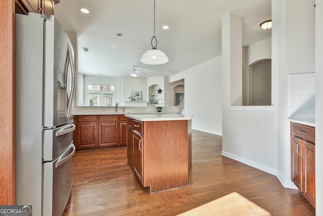 kitchen with decorative backsplash, dark hardwood / wood-style flooring, decorative light fixtures, stainless steel fridge with ice dispenser, and a kitchen island