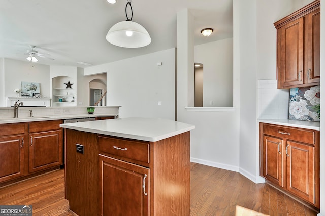 kitchen with ceiling fan, sink, light hardwood / wood-style flooring, pendant lighting, and a kitchen island