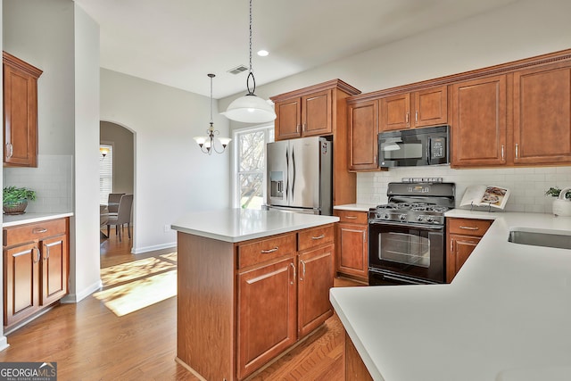 kitchen with backsplash, a center island, black appliances, and light hardwood / wood-style flooring