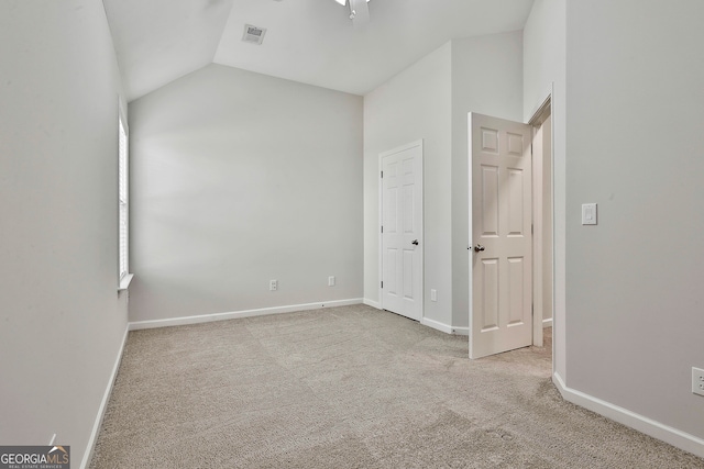 unfurnished bedroom with light colored carpet and lofted ceiling