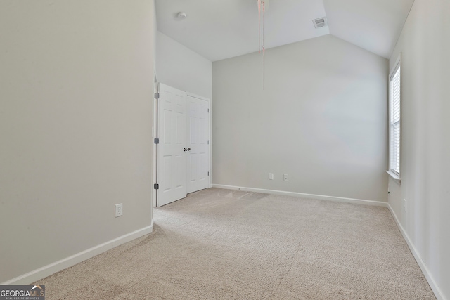 carpeted empty room featuring vaulted ceiling