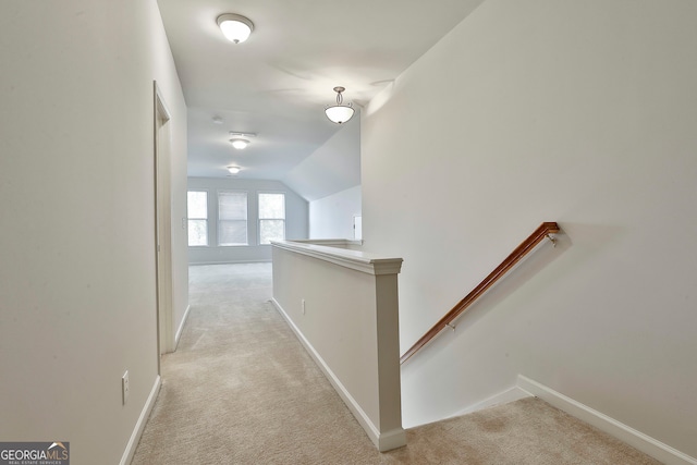 hallway featuring light carpet and vaulted ceiling