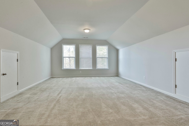 additional living space with light colored carpet and vaulted ceiling