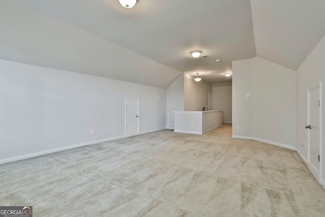 additional living space featuring light carpet and vaulted ceiling