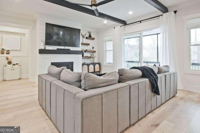 living room featuring a large fireplace, ceiling fan, light hardwood / wood-style floors, and ornamental molding