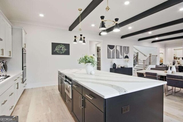 kitchen featuring beam ceiling, white cabinetry, hanging light fixtures, light hardwood / wood-style flooring, and a kitchen island