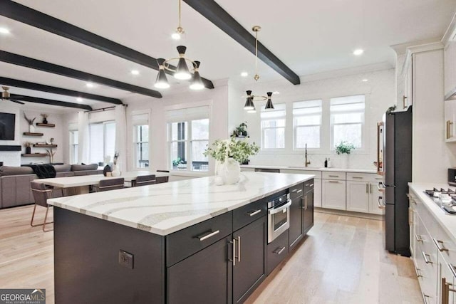 kitchen with a center island, stainless steel oven, white cabinets, light hardwood / wood-style flooring, and beamed ceiling