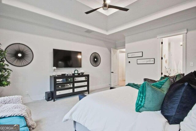 bedroom with ceiling fan, light carpet, and a tray ceiling