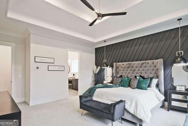 bedroom featuring a tray ceiling, ceiling fan, ensuite bathroom, and light colored carpet