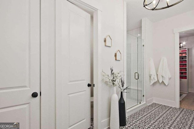 bathroom with hardwood / wood-style floors, an enclosed shower, and a notable chandelier