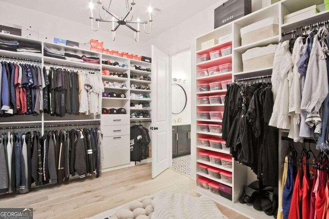 spacious closet featuring light hardwood / wood-style flooring and a chandelier