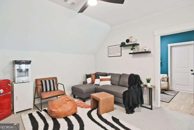 living room featuring ceiling fan, light hardwood / wood-style flooring, and vaulted ceiling