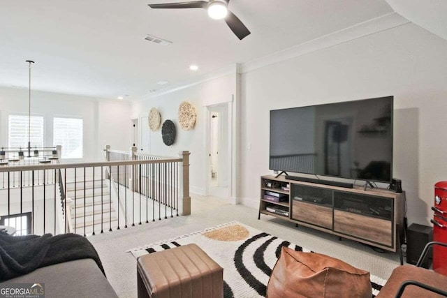 living room featuring ceiling fan, light colored carpet, and crown molding