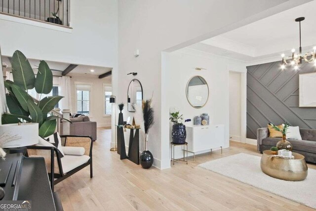 entryway featuring light wood-type flooring, a towering ceiling, and a chandelier