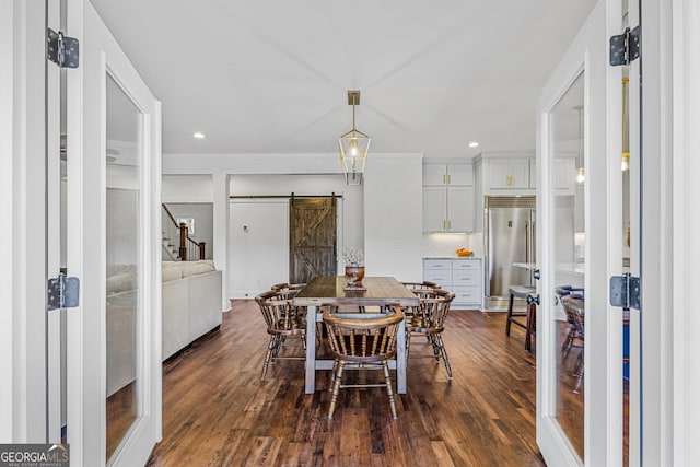 dining area featuring a barn door, dark hardwood / wood-style flooring, and ornamental molding