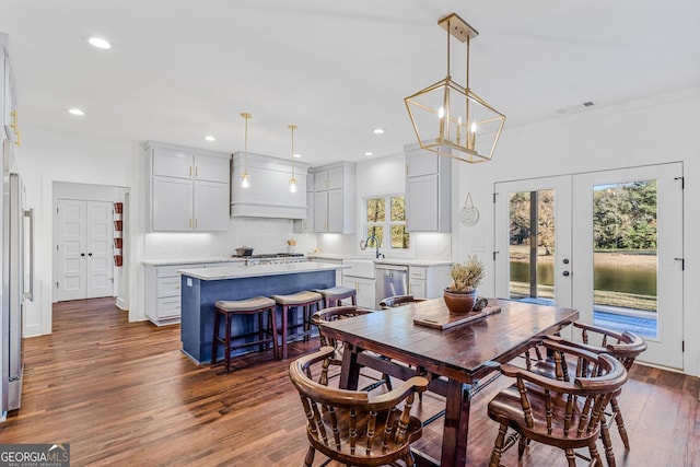 dining space with french doors, crown molding, sink, a notable chandelier, and dark hardwood / wood-style floors