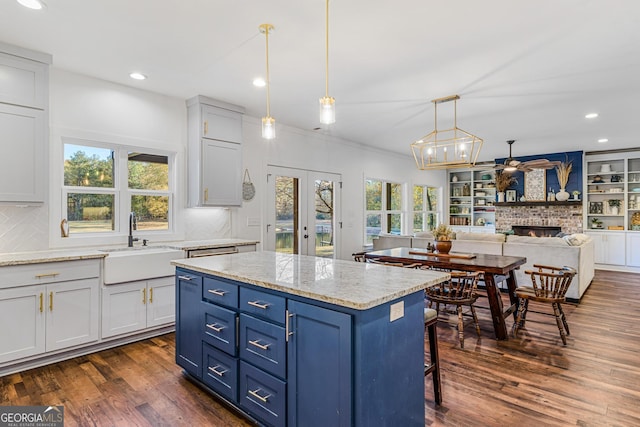 kitchen with a fireplace, a healthy amount of sunlight, sink, and dark wood-type flooring