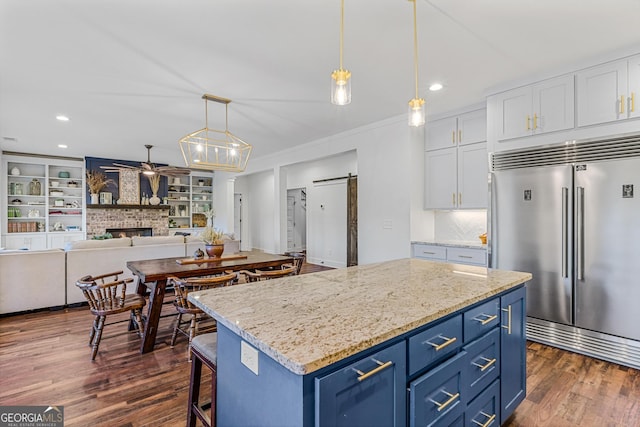 kitchen featuring built in fridge, a barn door, dark hardwood / wood-style flooring, and white cabinetry