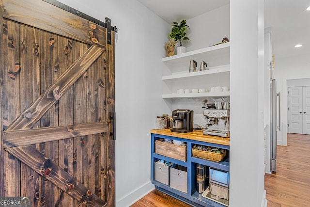 bar featuring decorative backsplash, hardwood / wood-style floors, and a barn door