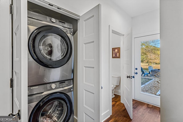 clothes washing area with dark hardwood / wood-style flooring and stacked washer and dryer