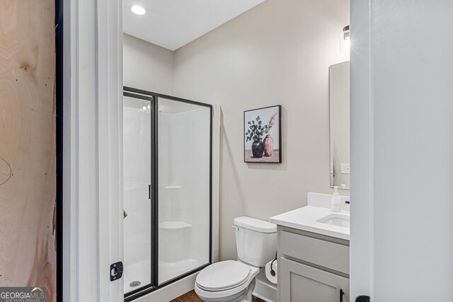 bathroom featuring vanity, toilet, and a shower with shower door