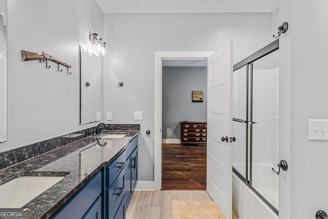 bathroom with hardwood / wood-style flooring, vanity, and bath / shower combo with glass door