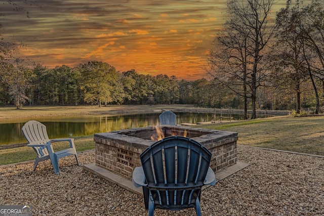 yard at dusk with a fire pit and a water view