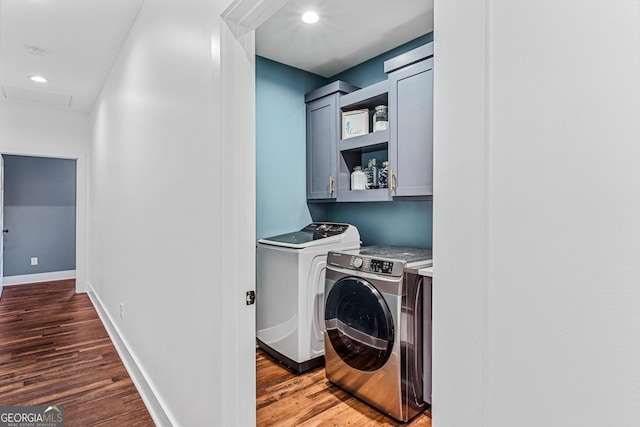 washroom featuring hardwood / wood-style flooring, washer and clothes dryer, and cabinets