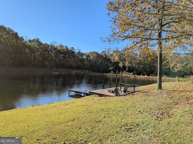 view of dock with a water view and a lawn