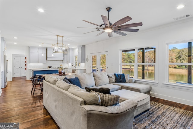 living room with french doors, sink, dark hardwood / wood-style flooring, ceiling fan with notable chandelier, and ornamental molding