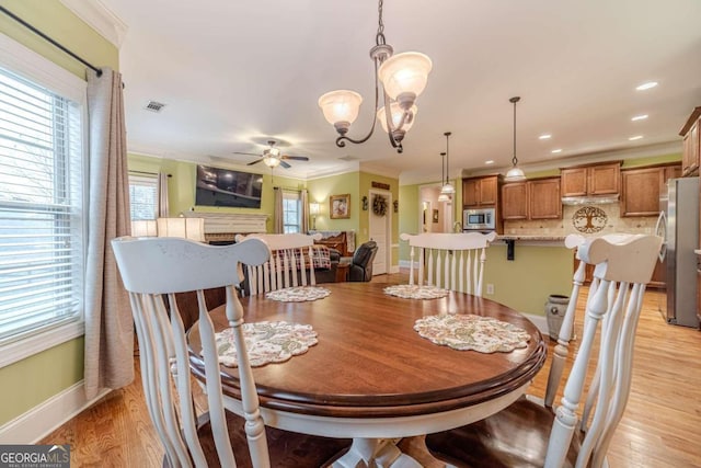 dining space featuring ceiling fan with notable chandelier, light hardwood / wood-style floors, and ornamental molding