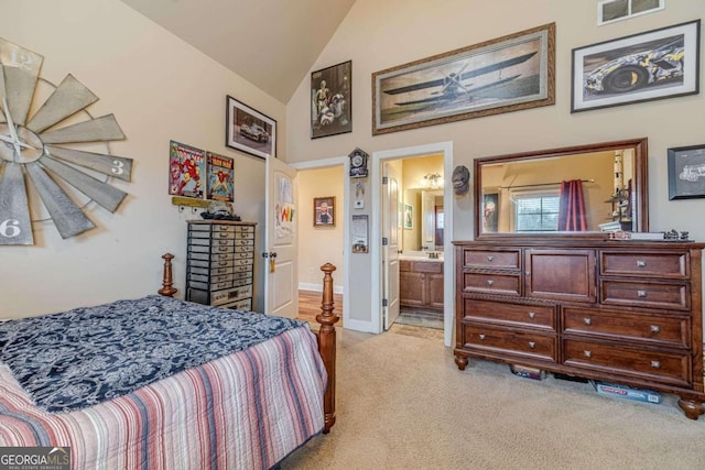 bedroom featuring light carpet, high vaulted ceiling, and ensuite bath