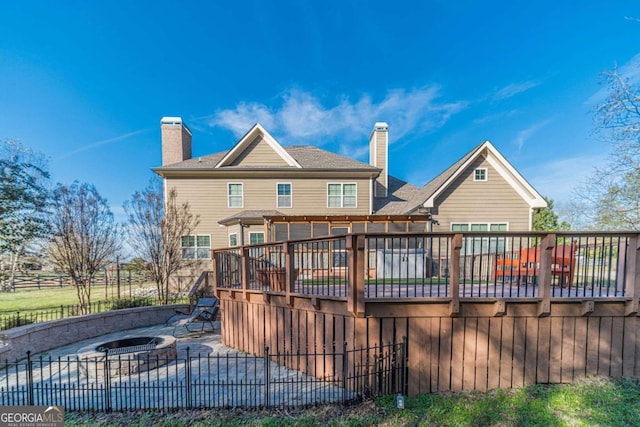 rear view of property featuring a wooden deck and a fire pit