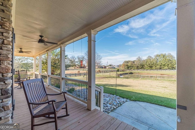 deck featuring covered porch, a rural view, ceiling fan, and a lawn