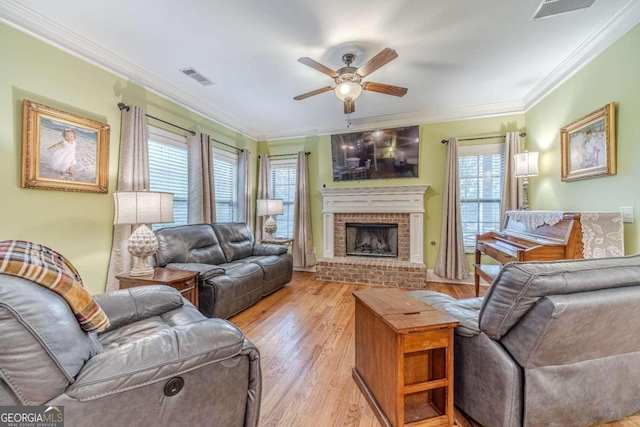 living room featuring a fireplace, plenty of natural light, ornamental molding, and light wood-type flooring