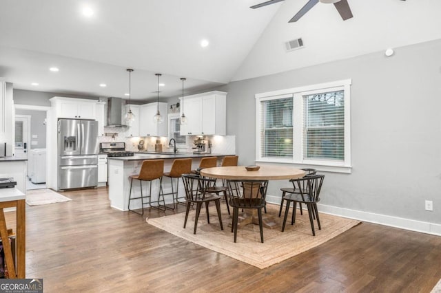 dining room featuring ceiling fan, dark hardwood / wood-style flooring, lofted ceiling, and sink