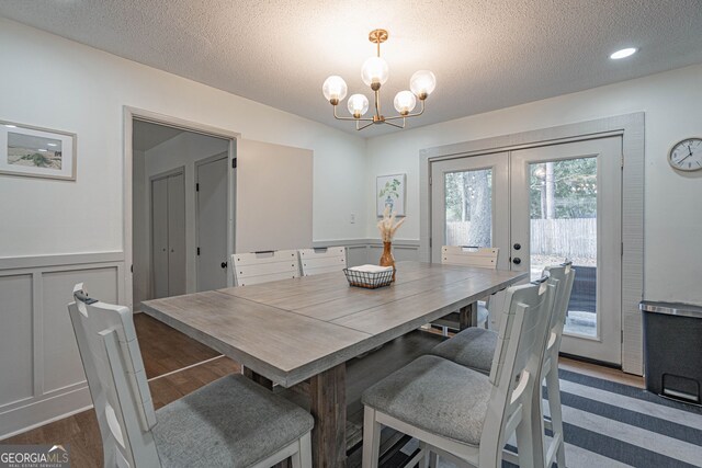 115 Lucian Cir, Savannah, GA 31406 - dining space with french doors, a textured ceiling, a chandelier, a wainscoted wall, and a decorative wall