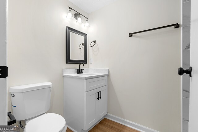 bathroom with hardwood / wood-style floors, vanity, and toilet