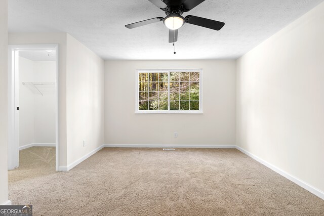 carpeted empty room featuring ceiling fan and a textured ceiling